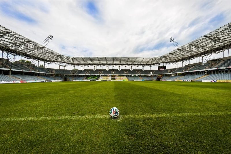 A ball on a pitch on an empty stadium
