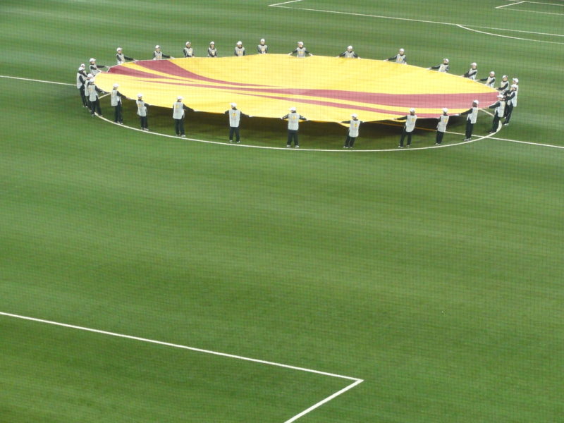 People holding a Europa League logo on the pitch
