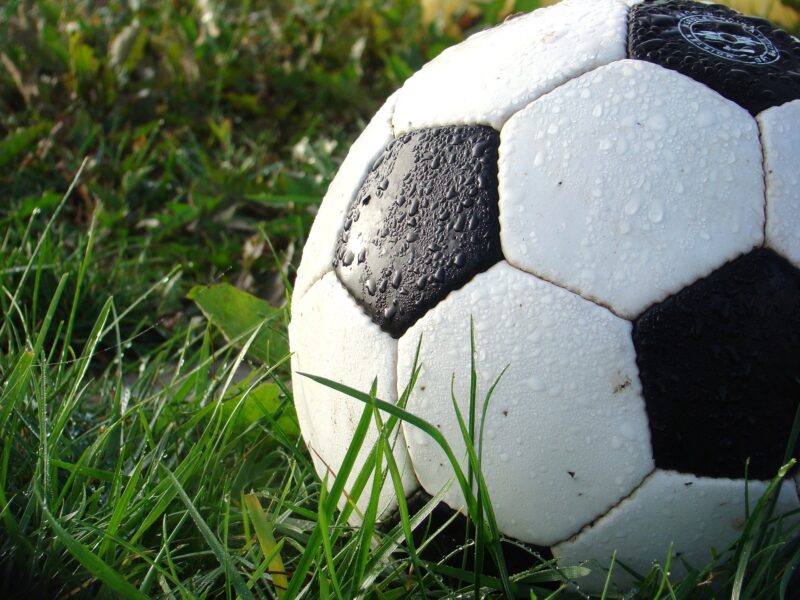 A closeup of a wet football in the grass