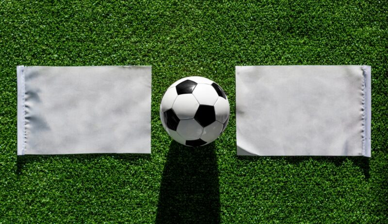 A football between two white flags on grass