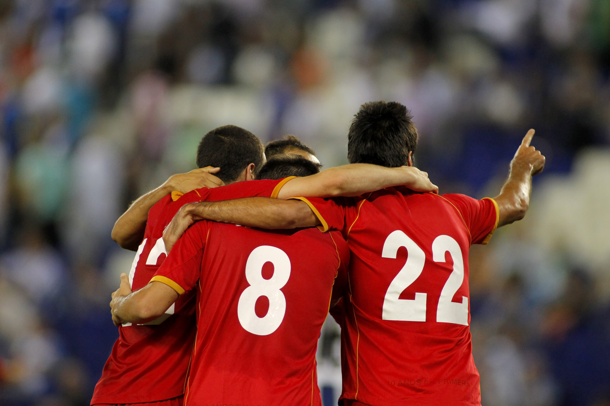 Three football players hugging each other and celebrating scoring a goal.