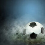 a picture of a football ball floating above the field in a hale of clouds.