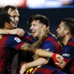 A group of Barcelona players hugging each other celebrating a goal