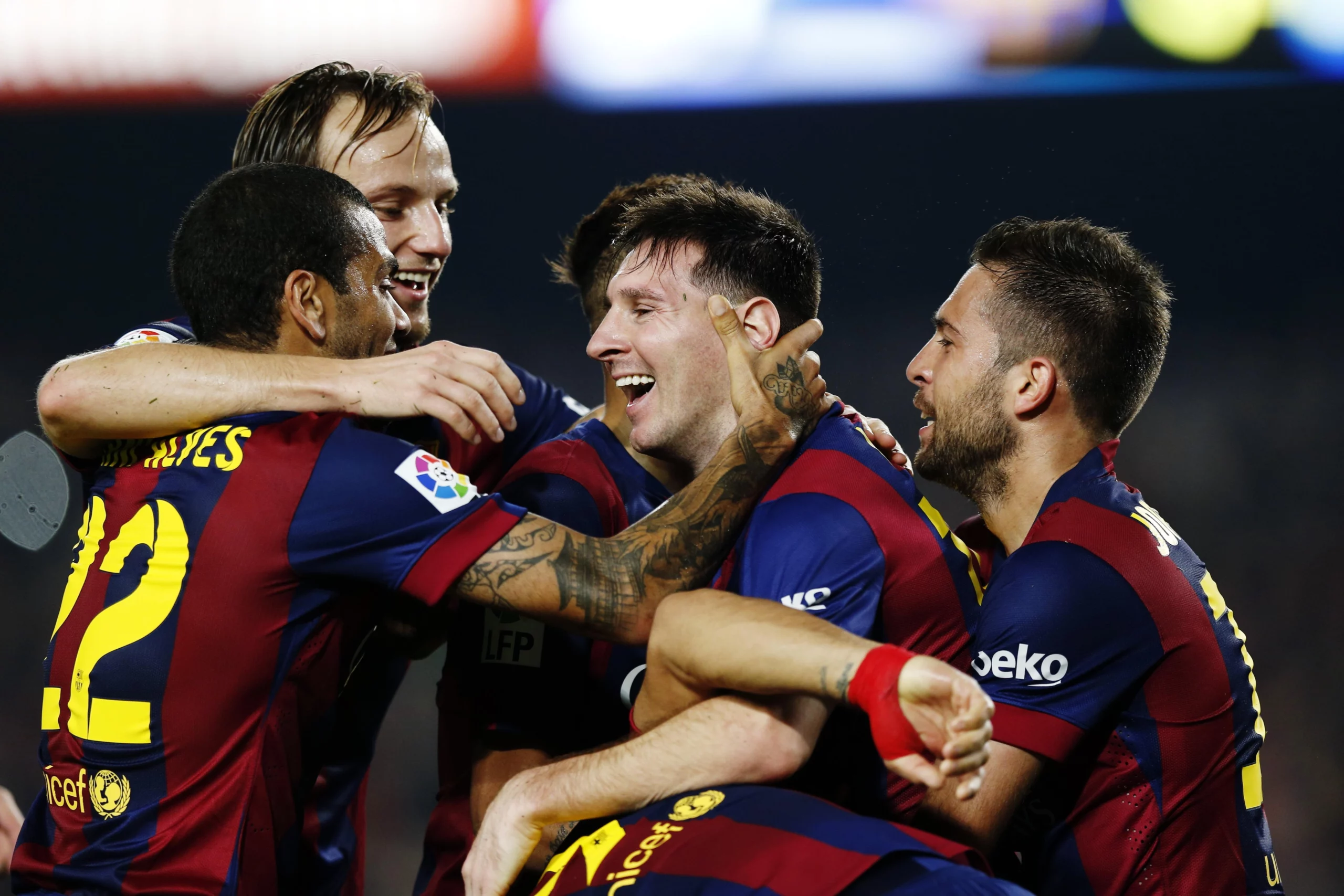 A group of Barcelona players hugging each other celebrating a goal